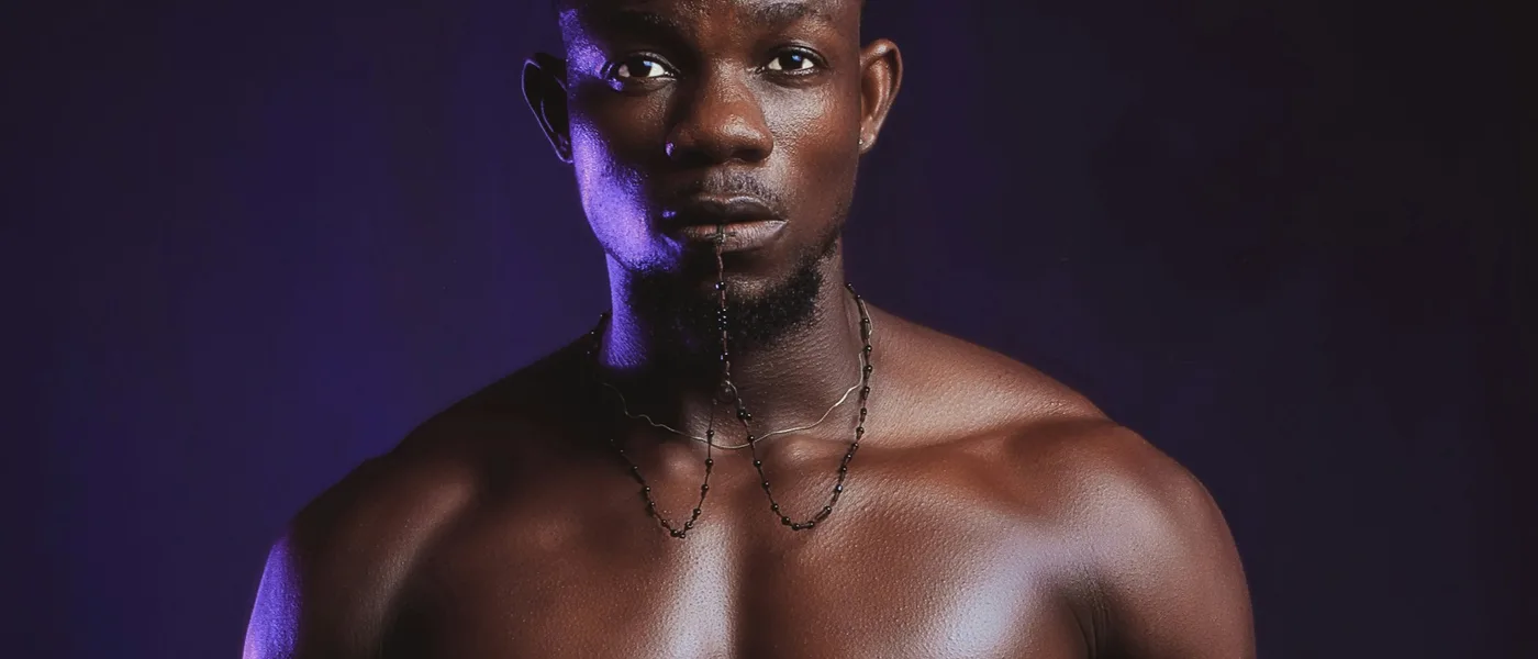 An athlete standing still in violet studio light, shoulders squared to the camera.